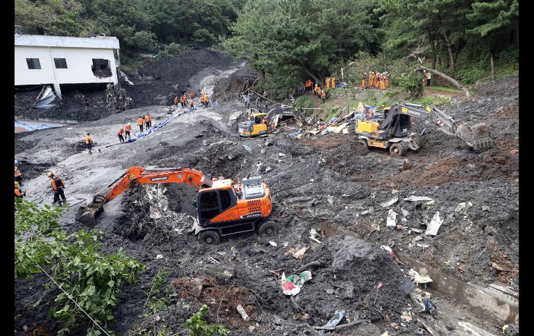 Rescatistas buscan a personas tras un deslave en Busan.