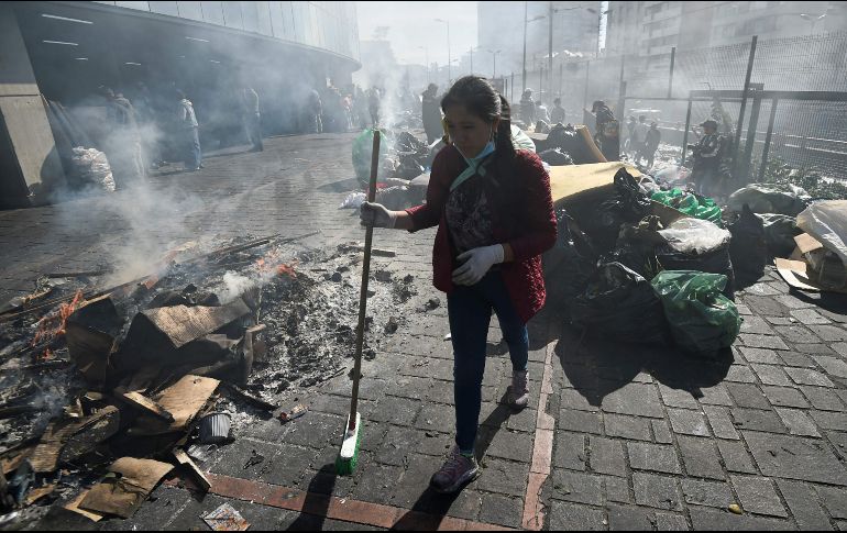 Una mujer barre los desechos abandonados en calles de Quito tras las protestas. AFP/L. Robayo