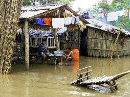 Dos niños secan maíz afuera de su vivienda en la poblacion de La Herradura. AFP/ARCHIVO