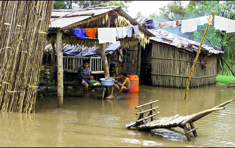 Dos niños secan maíz afuera de su vivienda en la poblacion de La Herradura. AFP/ARCHIVO