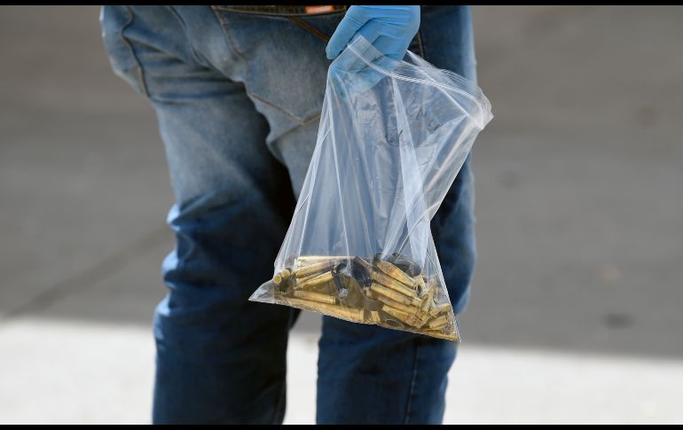 Un trabajador del servicio forense recoge casquillos en una calle. AFP/A. Estrella