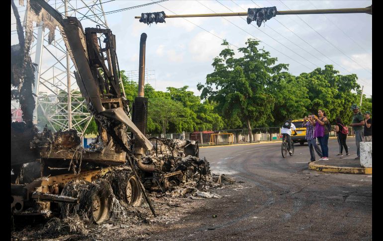 Personas toman fotos a los restos de un tráiler quemado en los hechos violentos de la víspera en Culiacán, Sinaloa. AP/A. Zurita