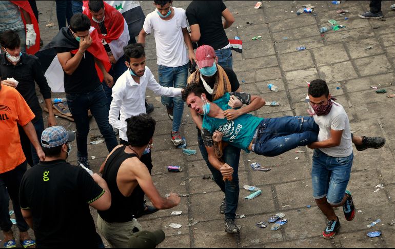 Manifestantes trasladan a un compañero herido durante una protesta en Bagdad. AP/H. Mizban