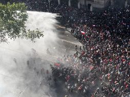 Policías arrojan chorros de agua contra manifestantes en Santiago. AP/E. Felix