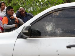 Varias personas observan el coche en el que viajaban los indígenas atacados; al auto se le aprecian varios impactos de bala. EFE/E. Guzmán