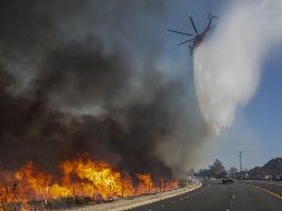 Un helicóptero descarga sobre una carretera en Simi Valley. AFP/D. McNew