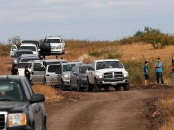 El convoy de vehículos que acuden al funeral se detuvo ayer en el sitio donde una de las mujeres de la familia LeBarón y sus hijos fueron asesinados. AFP/H. Martínez
