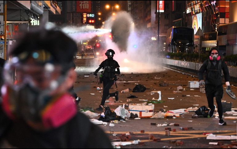 Manifestantes huyen luego de que la policía lanzara un cañón de agua en el distrito Mong Kok. AFP/P. Fong