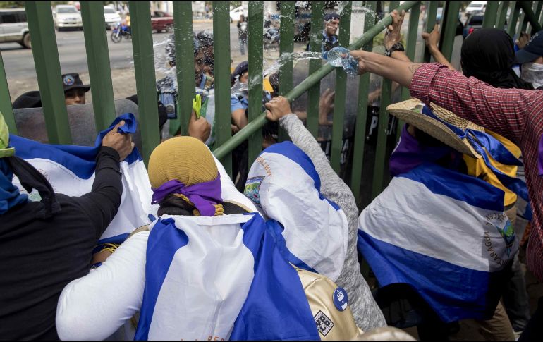 Estudiantes lanzan agua contra agentes antidisturbios durante una protesta en demanda de la liberación de los presos políticos en la Universidad Centroamericana (UCA), en Managua. EFE/J. Torres