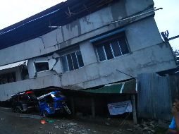 Unos vehículos pequeños se ven bajo una casa dañada por el sismo en Padada. AFP/F. Cabrera