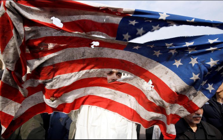 Un manifestante rompe una bandera estadounidense durante una manifestación multitudinaria contra EU en Teherán, después de que el Pentágono reivindicase el bombardeo selectivo que acabó con la vida de Qasem Soleimaní. EFE / A. Taherkenareh