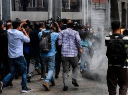 Periodistas y diputados de oposición también se enfrentaron a gases lacrimógenos lanzados afuera del Palacio Federal de la Asamblea en Caracas. AFP/Y. Cortez