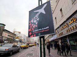 Ciudadanos iraníes caminan cerca de un póster que condena el derribo del avión ucraniano por parte del Ejército. EFE/A. Taherkenareh