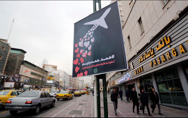 Ciudadanos iraníes caminan cerca de un póster que condena el derribo del avión ucraniano por parte del Ejército. EFE/A. Taherkenareh
