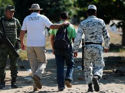 Un trabajador del Instituto Nacional de Migración escolta hoy a un migrante que cruzó a Ciudad Hidalgo, Chiapas, tras nadar por el río Suchiate. AP/M. Ugarte