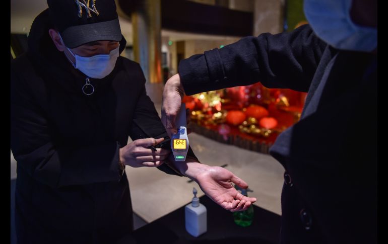 Un trabajador de un hotel toma la temperatura a una persona que va llegando. AFP/H. Retamal