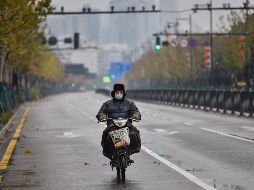 Un hombre conduce por una calle casi vacía en Wuhan. Autoridades decretaron medidas extremas frente al coronavirus como el cierre de los accesos a la ciudad, incluido el aeropuerto, y la suspensión de todos los servicios de transporte desde el 23 de enero. AFP/H. Retamal