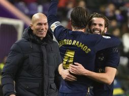 CELEBRACIÓN. Sergio Ramos abraza a Nacho, autor del gol madrileño, festejo al que se unió el DT Zinedine Zidane. AFP