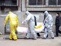 Trabajadores de una funeraria trasladan el cuerpo de una persona sospechosa de haber muerto de coronavirus en Wuhan, China. AP/Chinatopix