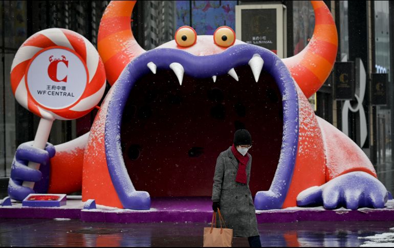 Una mujer con una mascarilla camina junto a un centro comercial en Pekín. AFP/W. Zhao