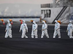 Personal con atuendos protectores se ve cerca del crucero Diamond Princess, en cuarentena en Yokohama, Japón. En el barco se han detectado 135 casos confirmados del coronavirus. AFP/C. Triballeau