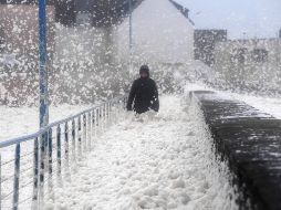 Una persona camina entre espuma de mar en Saint-Guenole, Francia, por los efectos de la tormenta. AFP/F. Tanneau