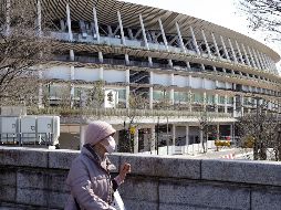 Una mujer con mascarilla pasa por el Estadio Nacional, donde será la apertura de los Juegos Olímpicos de Tokio. Hasta ahora los Juegos están programados para arrancar el 24 de julio. EFE/EPA/K. Mayama