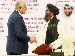 Zalmay Khalilzad (i) y Abdul Ghani Baradar se dan la mano en medio de los aplausos de los asistentes. EFE