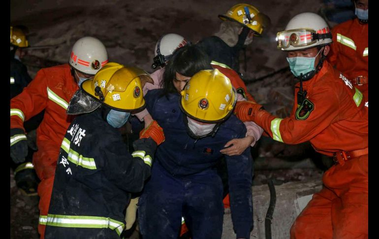 Trabajadores de rescate, vestidos con overoles anaranjados, trepan sobre escombros y estructuras metálicas retorcidas del hotel para sacar a las víctimas. AFP