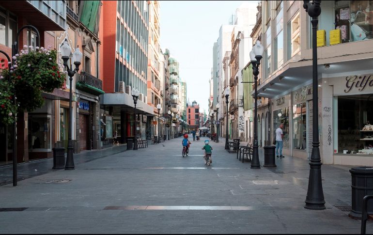 Unos niños juegan este sábado con sus bicicletas por la calle Triana, uno de los principales centros comerciales de Madrid que luce semivacío este sábado. EFE/A. Medina