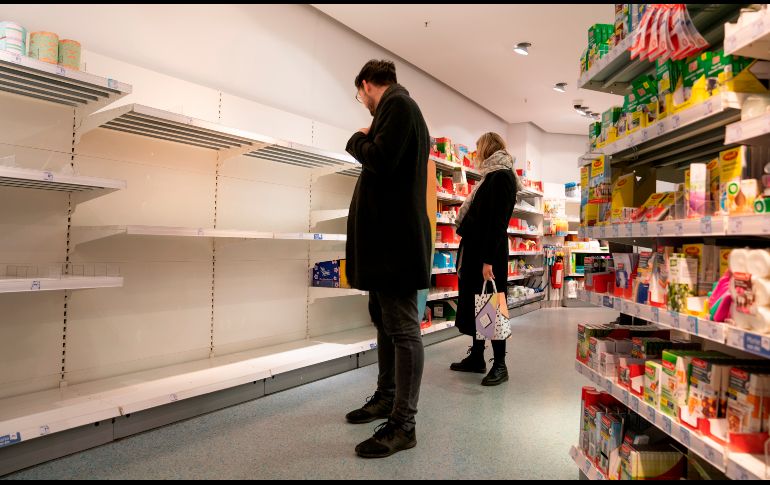 Aunque no es un artículo de primera necesidad que se recomiende para hacer frente a la pandemia, el papel de baño escasea en tiendas de varios países. Clientes en una farmacia en Berlín, Alemania, miran los anaqueles vacíos del papel higiénico. EFE/A. Becher