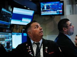 Corredores en la bolsa de Nueva York reaccionan mientras el presidente Trump habla  en rueda de prensa en la Casa Blanca. AFP/S. Platt