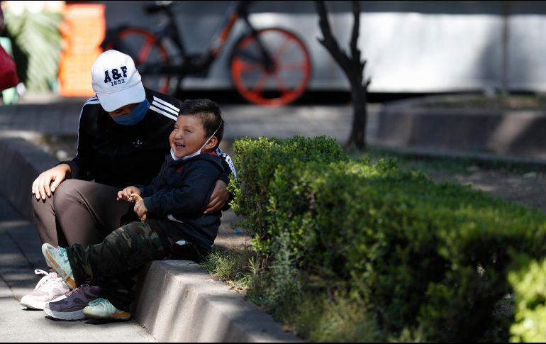 Una mujer cubierta con un cubrebocas platica con su hijo en un parque. AP/R. Blackwell