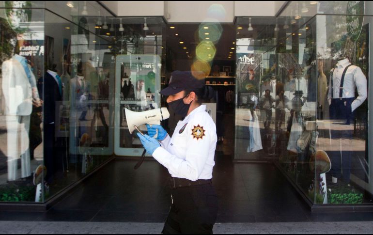 Una policía advierte a personas en la calle ayer en Monterrey, Nuevo León, que se queden en sus casas para evitar la expansión del COVID-19. AFP/ARCHIVO