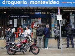 Personas hacen fila en una droguería para adquirir productos como alcohol líquido y en gel en Montevideo. EFE/R. Martínez