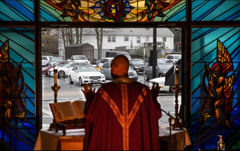 Un sacerdote oficia misa desde un templo católico en Johnston, en el estado de Rhode Island  mientras fieles escuchan la ceremonia desde sus carros, como parte de las medidas de distanciamiento social. AP/D. Goldman
