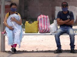 Dos personas esperan en un paradero de autobuses en Tegucigalpa. EFE/G. Amador