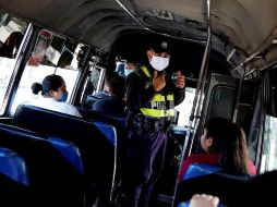Un agente policial inspecciona que el trasporte público cumpla con normas de seguridad sanitaria en San Salvador. EFE/R. Sura