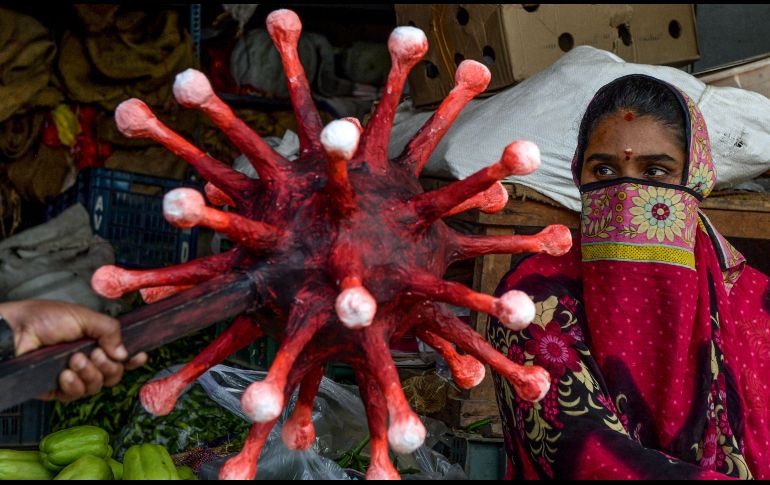Un policía con un bastón con una figura de coronavirus realiza una campaña sobre la importancia de respetar las medidas para evitar los contagios en Chennai, India. AFP/A. Sankar