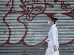 Una enfermera camina en una calle de San Salvador. EFE/R. Sura