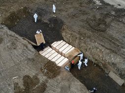 Trabajadores en atuendos protectores entierran hoy cuerpos en  Hart Island, en la zona del Bronx en Nueva York. AP/J. Minchillo