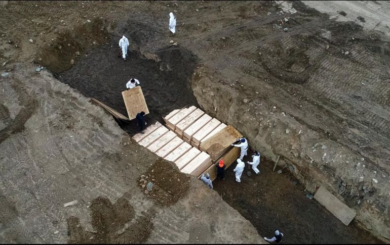 Trabajadores en atuendos protectores entierran hoy cuerpos en  Hart Island, en la zona del Bronx en Nueva York. AP/J. Minchillo