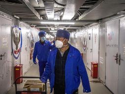 Trabajadores con máscaras protectoras caminan en el Hospital de Leishenshan, en Wuhan, China. EFE/R. Pilipey