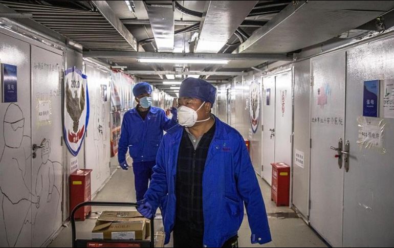 Trabajadores con máscaras protectoras caminan en el Hospital de Leishenshan, en Wuhan, China. EFE/R. Pilipey