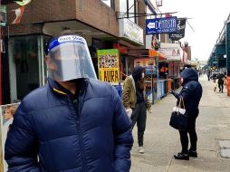 Un hombre protegido con cubrebocas y una mascarilla plástica camina por calles del distrito de Queens. EFE/J. Fuentelsaz