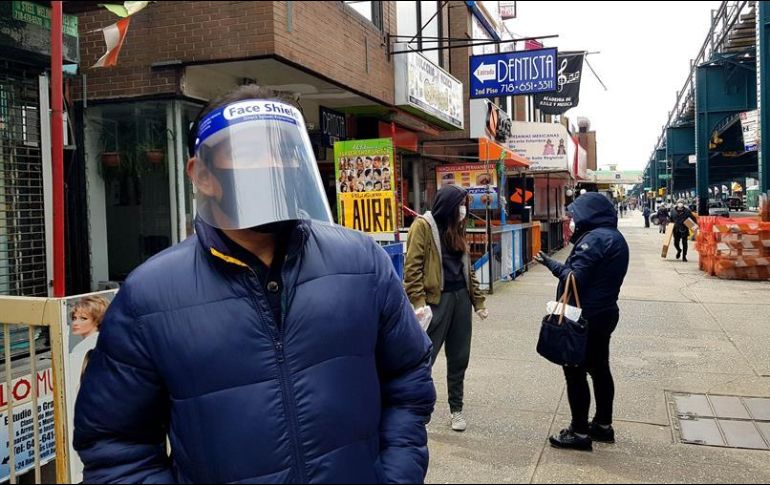 Un hombre protegido con cubrebocas y una mascarilla plástica camina por calles del distrito de Queens. EFE/J. Fuentelsaz