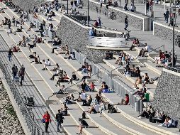 Personas toman hoy el Sol frente al río en Colonia, Alemania. Autoridades piden no bajar la guardia, pero las normas de distanciamiento social se han ido relajando en la práctica. AP/M. Meissner