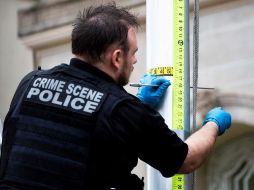 Un agente del Servicio Secreto de EU examina la trayectoria de una bala que atravesó un asta de bandera afuera de la Embajada de Cuba. EFE/M. Reynolds