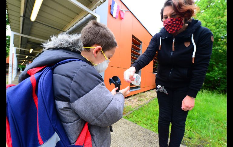 Una maestra aplica una solución desinfectante a un niño en una primaria en Cenon. AFP/M. Fedouach
