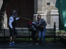 Aún no. Policías instan a unas personas a no sentarse en una banca bloqueada por una cinta amarilla. EL INFORMADOR/F. Atilano